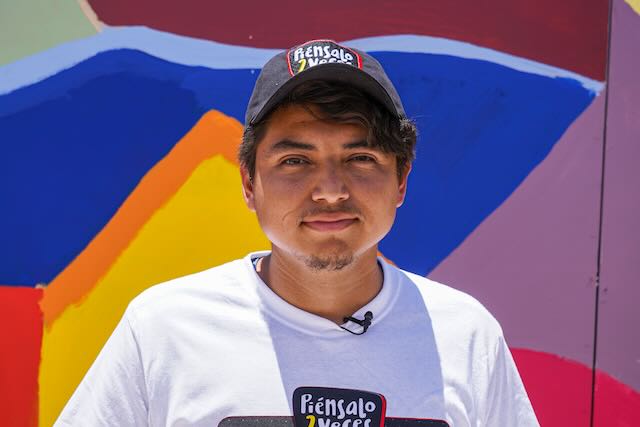 Fotografía: Retrato de un hombre joven que viste con una camisa y una gorra impresas con el logo de la campaña Piénsalo 2 Veces.