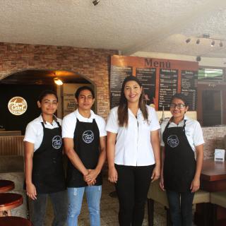 Group of four young people with aprons in a café